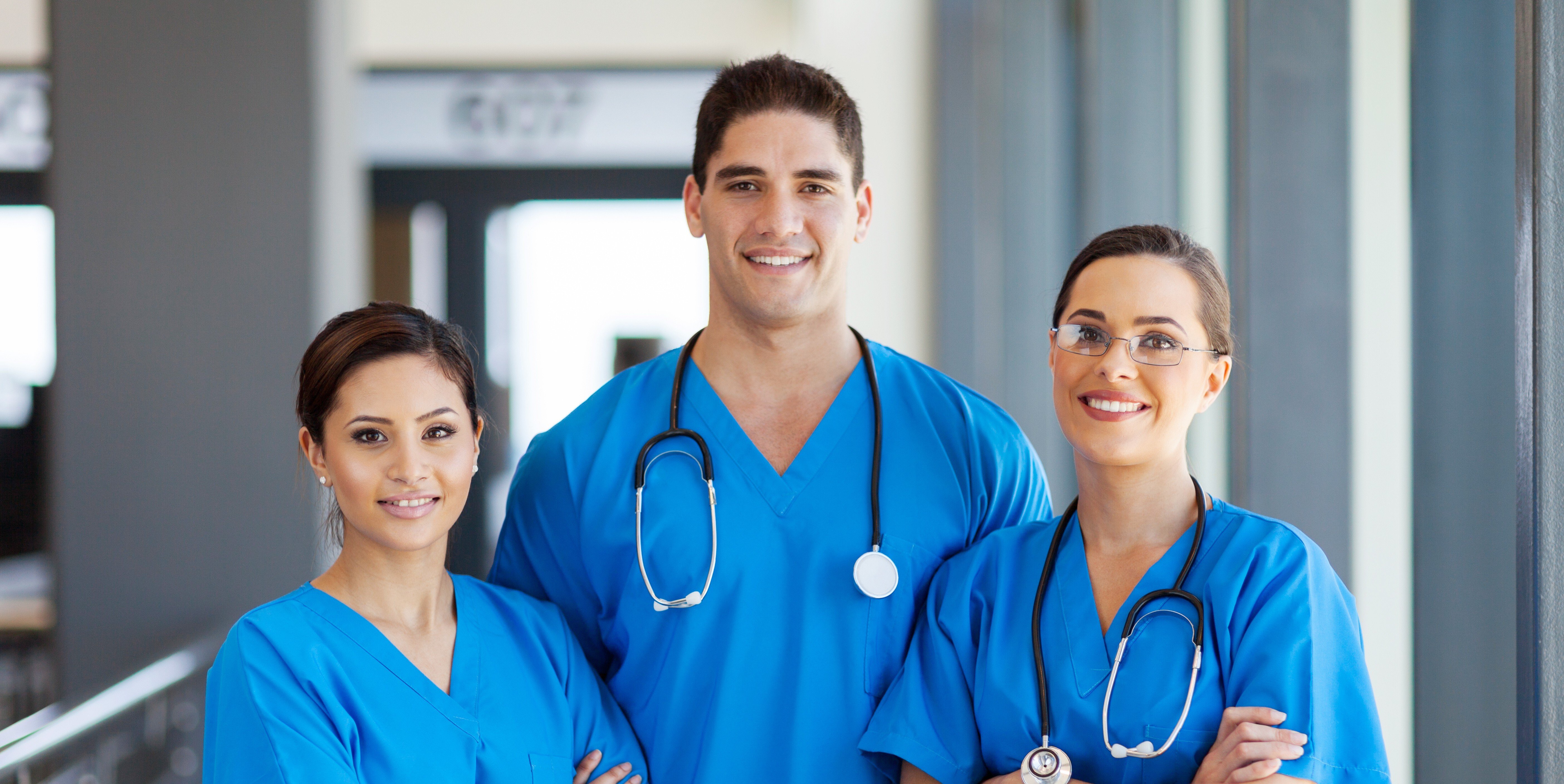 Healthcare professionals in blue scrubs standing together in a hospital setting, representing clinical workforce staffing and care delivery teams.