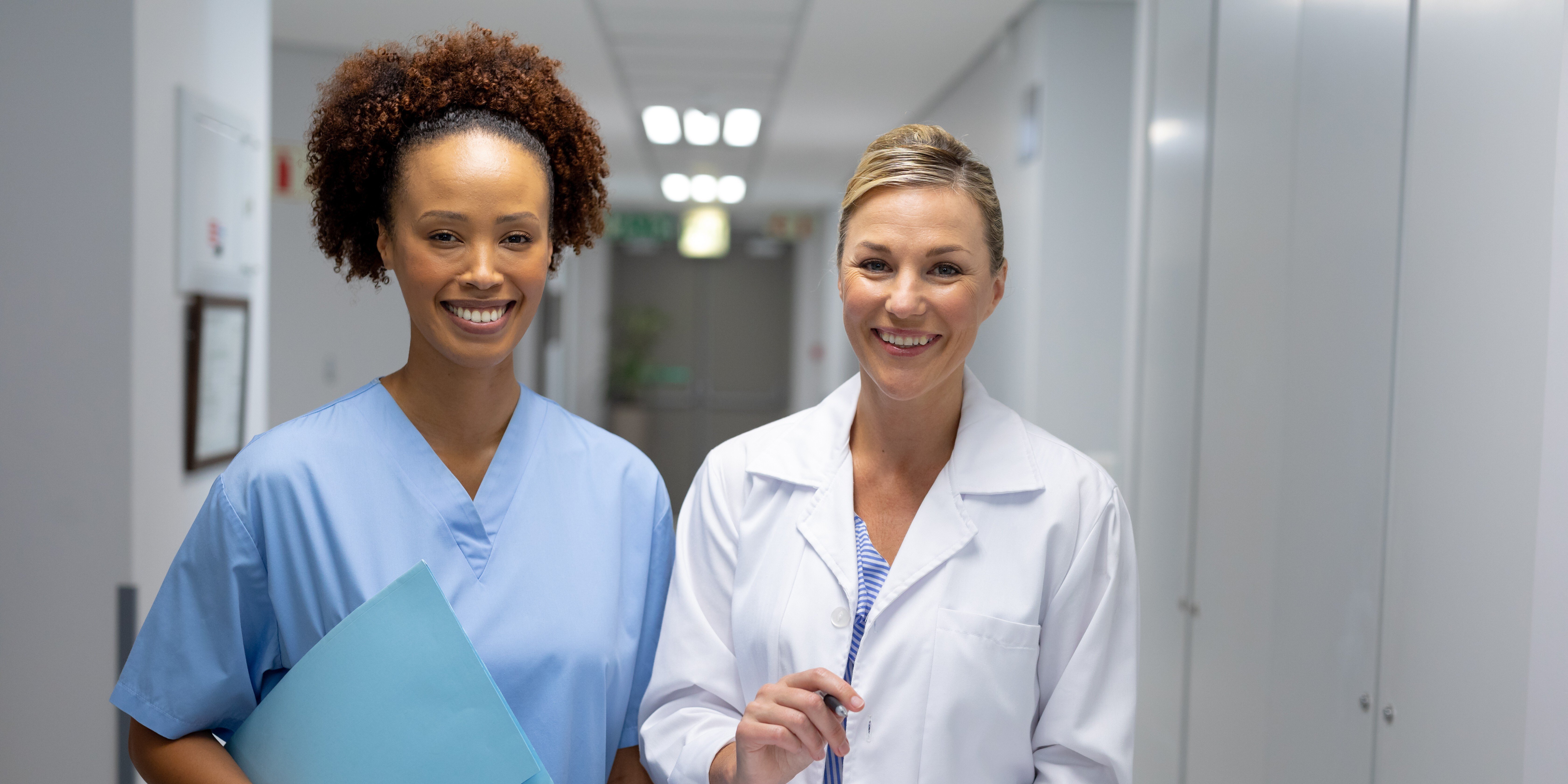 A nurse and a physician smiling in the hallway of the healthcare facility.